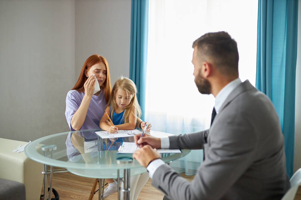 The mother is crying while explaining to the lawyer the situation.