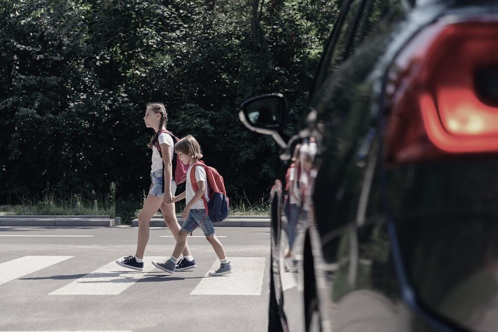 School children crossing street while car is stopping.
